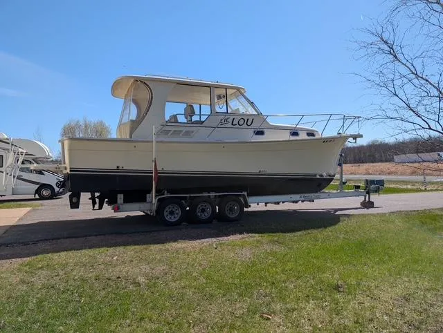Slide: The Image of 2010 Mainship Pilot 31 boat on trailer, parked on grass under clear blue sky. - 28