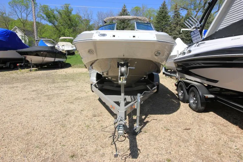 Slide: The Image of 2016 Crownline Eclipse E2 boat on trailer, parked outdoors with other boats. - 2