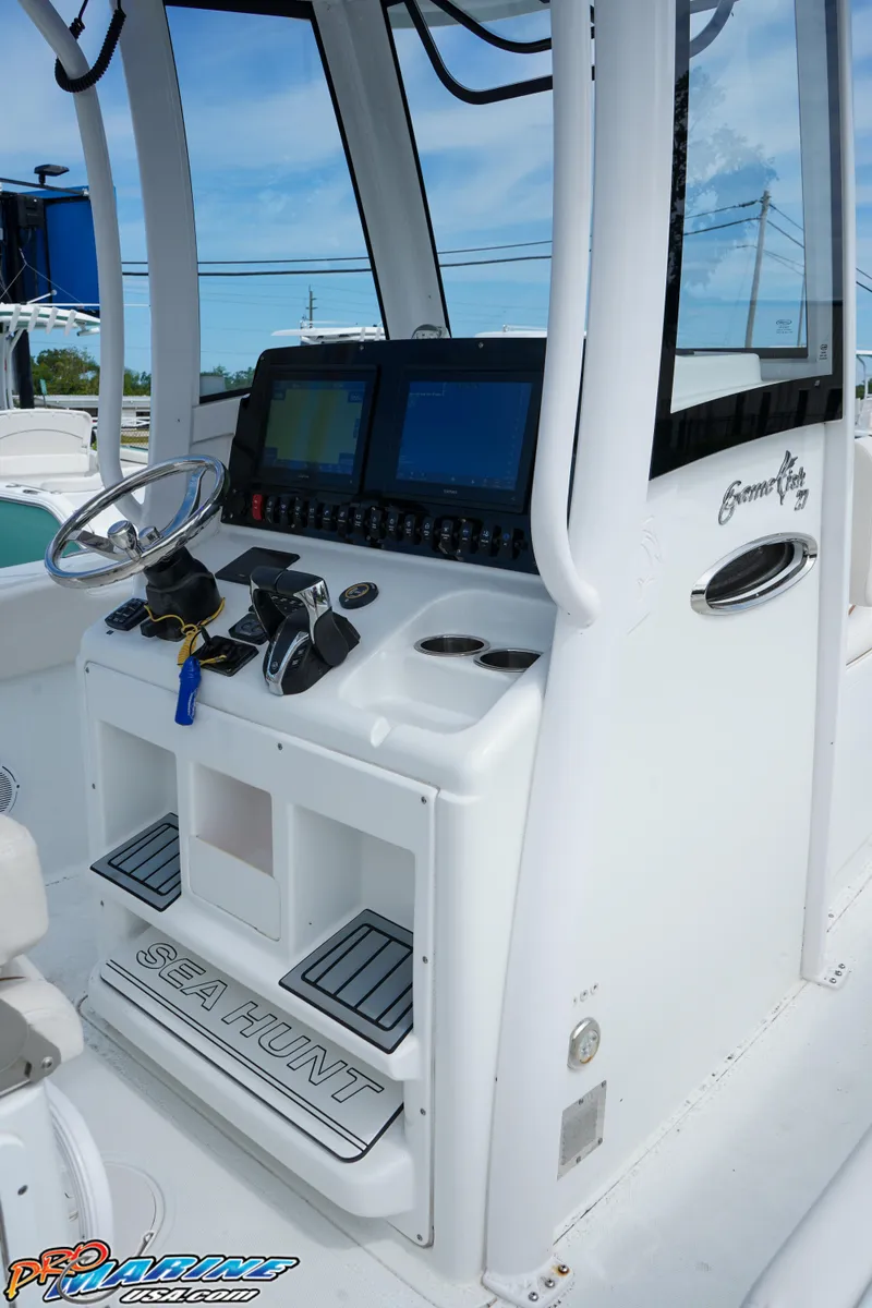 Slide: The Image of 2022 Sea Hunt GAMEFISH 27 CB console with steering wheel and navigation screens. - 36