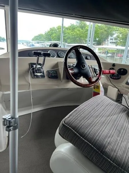 Slide: The Image of 2005 Carver Mariner 360 helm with steering wheel and controls, docked near greenery. - 4