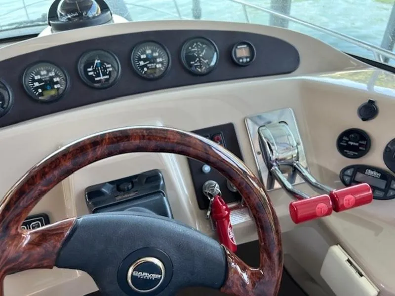 Slide: The Image of 2005 Carver Mariner 360 helm with gauges, wood-trimmed steering wheel, and throttle controls. - 20