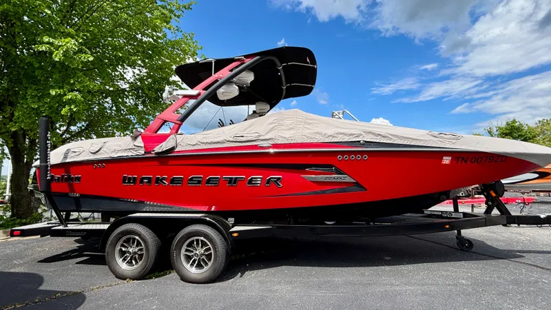 Slide: The Image of 2015 Malibu Wakesetter 22 MXZ boat on trailer, red with cover, parked outdoors. - 10