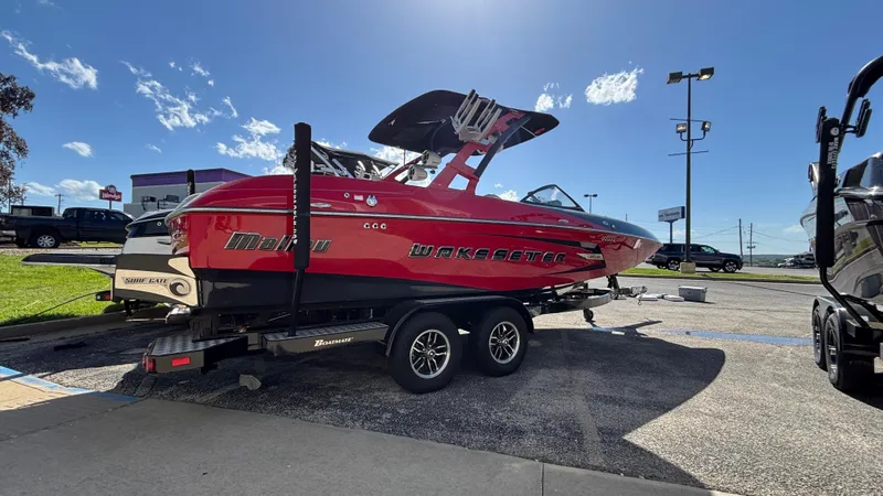 Slide: The Image of 2015 Malibu Wakesetter 22 MXZ boat on trailer, parked outdoors under clear sky. - 9