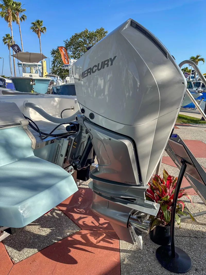 Slide: The Image of 2025 Caymas 24 HB boat with Mercury outboard motor, displayed outdoors with palm trees. - 12
