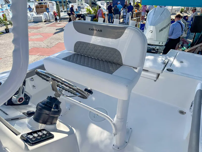 Slide: The Image of 2025 Caymas 24 HB boat interior with steering wheel and seating at a boat show. - 19
