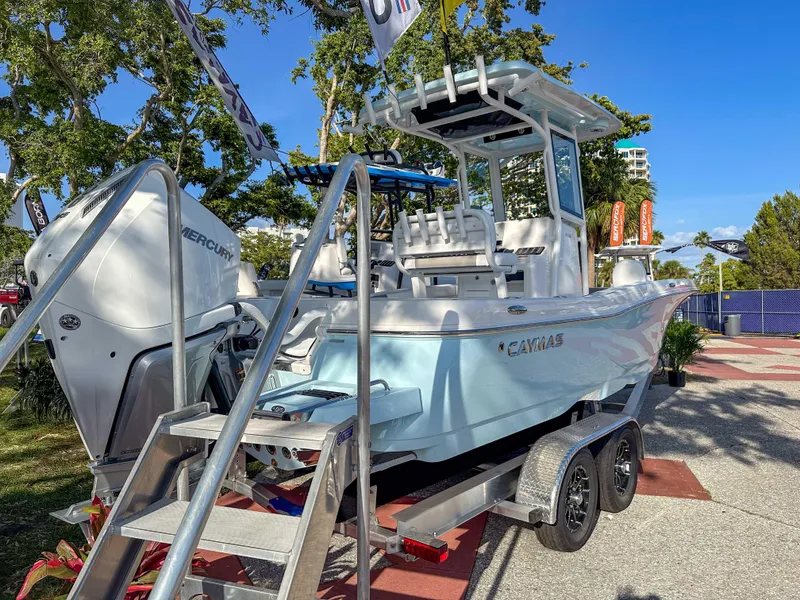 Slide: The Image of 2025 Caymas 24 HB boat on trailer, displayed outdoors with trees in background. - 2