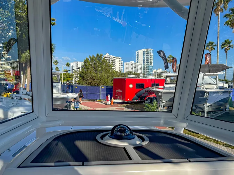 Slide: The Image of View from 2025 Caymas 24 HB boat cockpit, showcasing urban skyline and red trailer. - 22