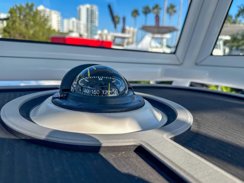 Slide: The Image of Compass on 2025 Caymas 24 HB boat with cityscape and palm trees in background. - 23