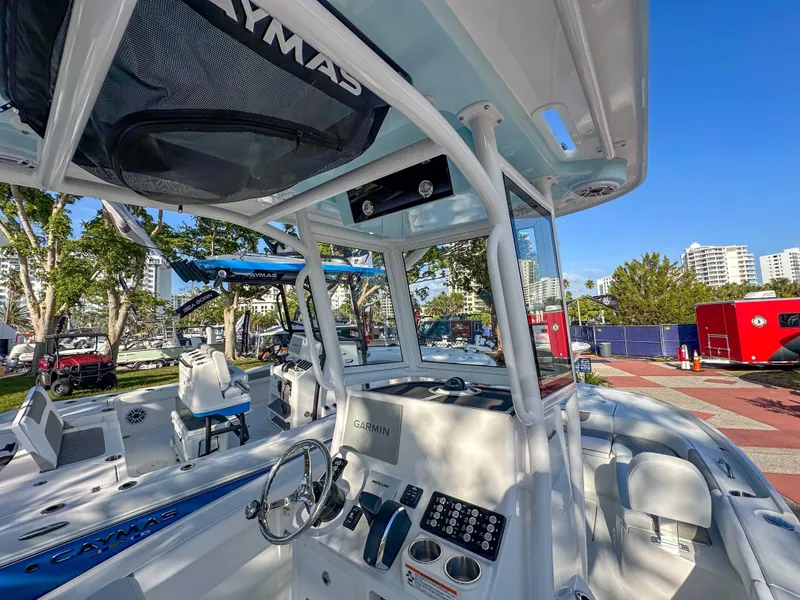 Slide: The Image of 2025 Caymas 24 HB boat interior with steering wheel and control panel, docked outdoors. - 25