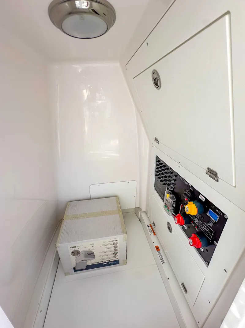 Slide: The Image of 2025 Caymas 24 HB boat interior compartment with electrical panel and storage. - 28