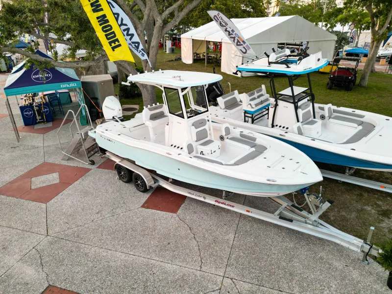 Slide: The Image of 2025 Caymas 24 HB boat displayed outdoors on a trailer at a boat show. - 3