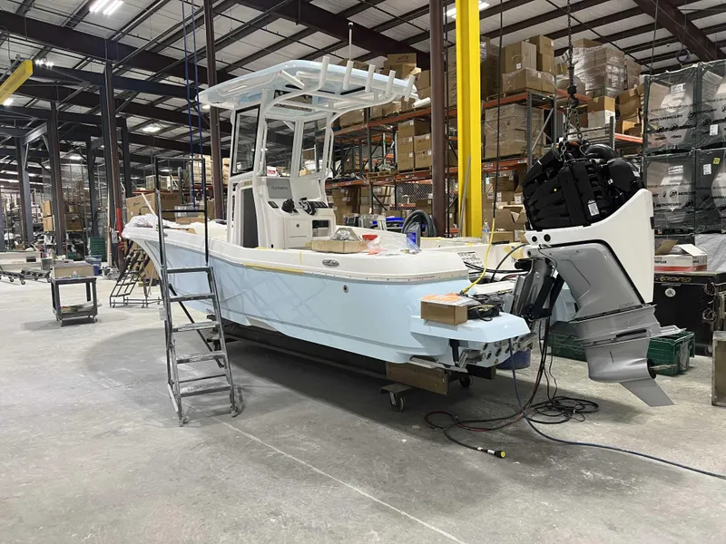 Slide: The Image of 2025 Caymas 24 HB boat in a warehouse, under construction with equipment and tools around. - 30