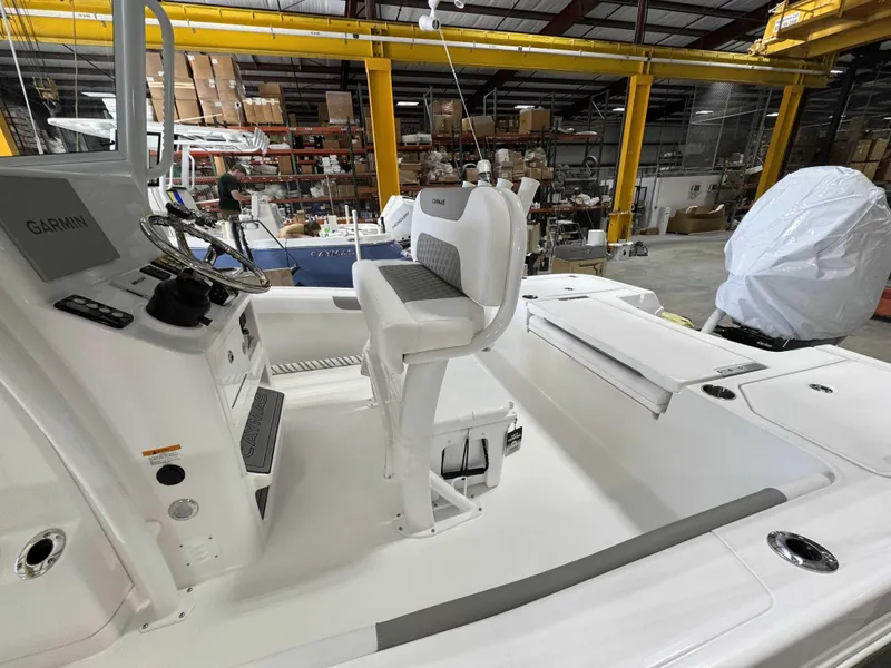 Slide: The Image of 2025 Caymas 24 HB boat interior with steering console and seating in a warehouse. - 31