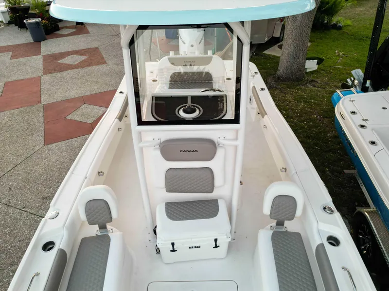 Slide: The Image of 2025 Caymas 24 HB boat interior with seating and console, docked outdoors. - 7
