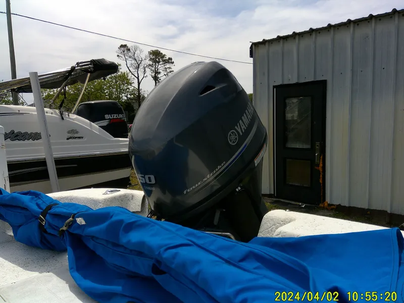 Slide: The Image of 2000 Carolina Skiff 1765 DLX with Yamaha outboard motor, blue cover, and nearby boats. - 17