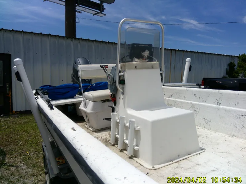 Slide: The Image of 2000 Carolina Skiff 1765 DLX boat with center console and seating, parked outdoors. - 6