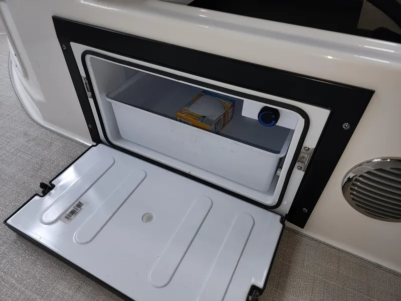 Slide: The Image of Open storage compartment on 2023 Regal 28 Express boat, featuring a small built-in cooler. - 7