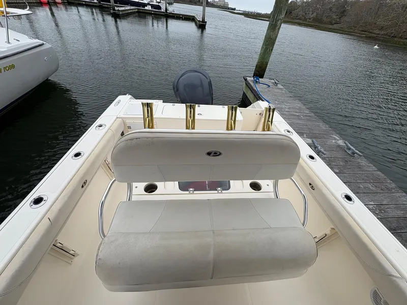 Slide: The Image of 2008 Pursuit 2570 CC boat interior with seating and rod holders at a dock. - 10