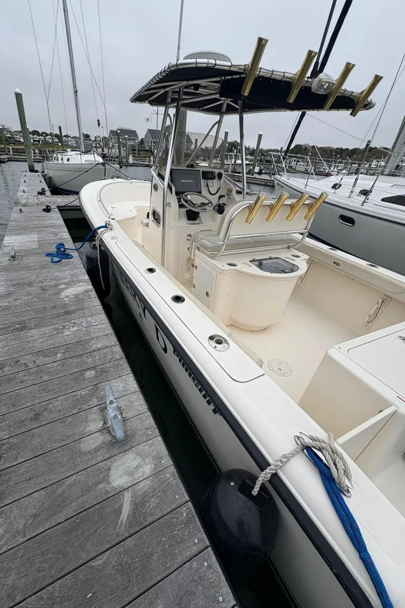 Slide: The Image of 2008 Pursuit 2570 CC boat docked at marina, featuring center console and fishing rod holders. - 16