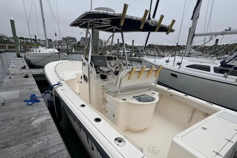 Slide: The Image of 2008 Pursuit 2570 CC boat docked, featuring center console and rod holders. - 17