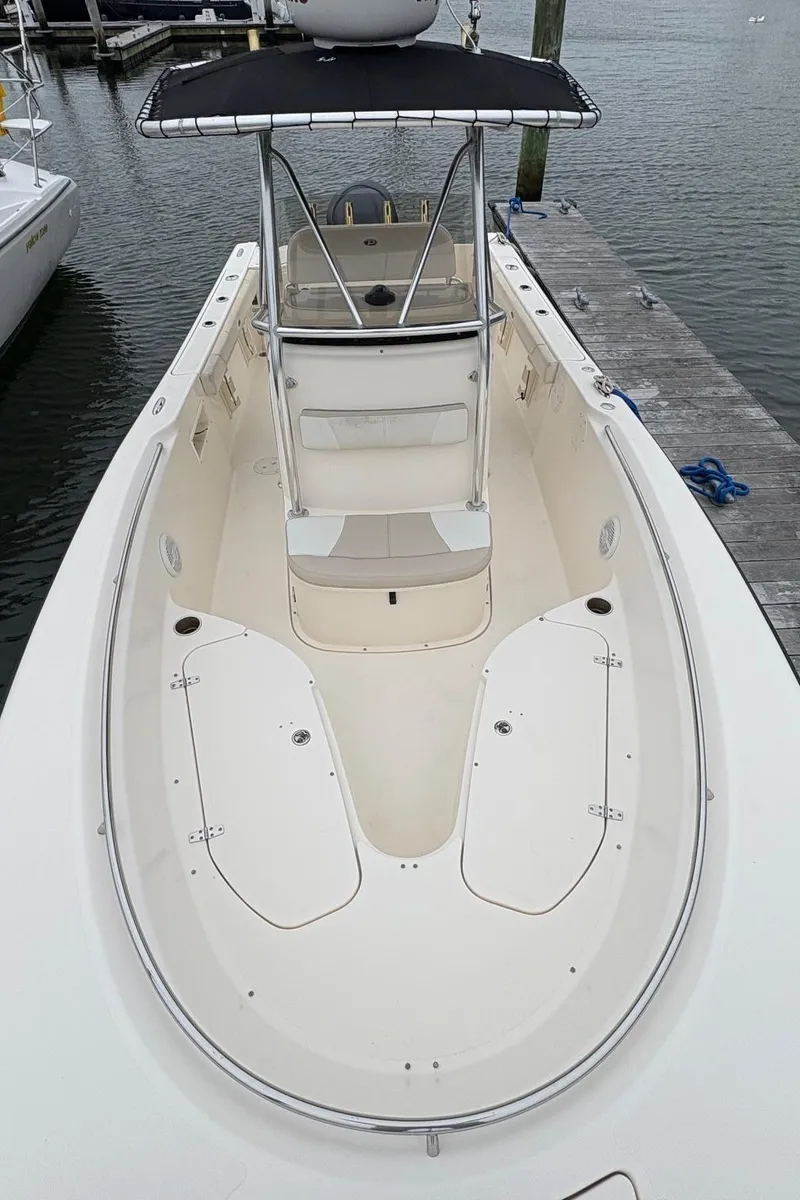 Slide: The Image of 2008 Pursuit 2570 CC boat docked, featuring spacious deck and T-top canopy. - 19
