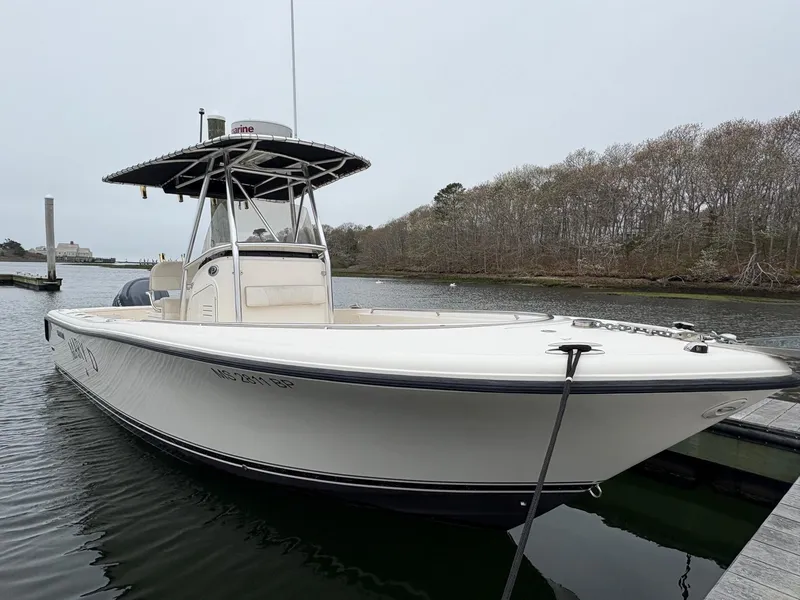 Slide: The Image of 2008 Pursuit 2570 CC boat docked on calm water, featuring a sleek design and T-top. - 2