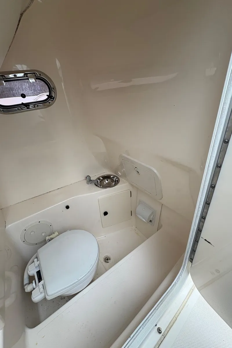 Slide: The Image of 2008 Pursuit 2570 CC boat interior with compact marine toilet and sink. - 23