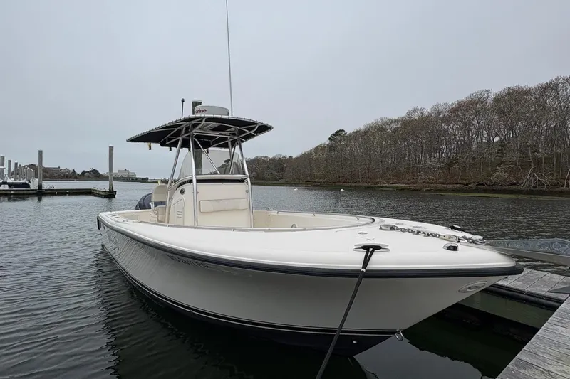Slide: The Image of 2008 Pursuit 2570 CC boat docked on calm water near a wooded shoreline. - 3