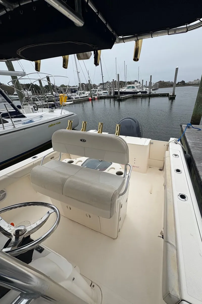 Slide: The Image of 2008 Pursuit 2570 CC boat docked at marina, featuring spacious seating and steering console. - 6