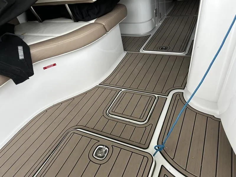 Slide: The Image of Interior of a 2010 Cobalt 302 boat with teak-style flooring and beige seating. - 28