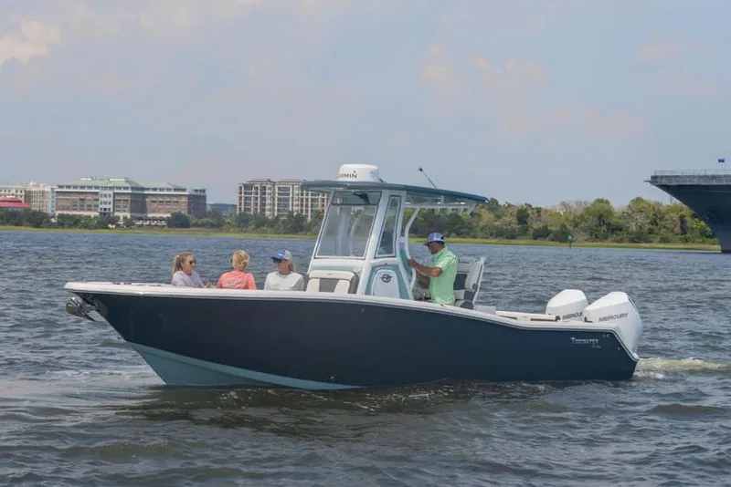 Slide: The Image of 2025 Tidewater 272 CC Adventure boat on trailer, side view, under clear blue sky. - 0