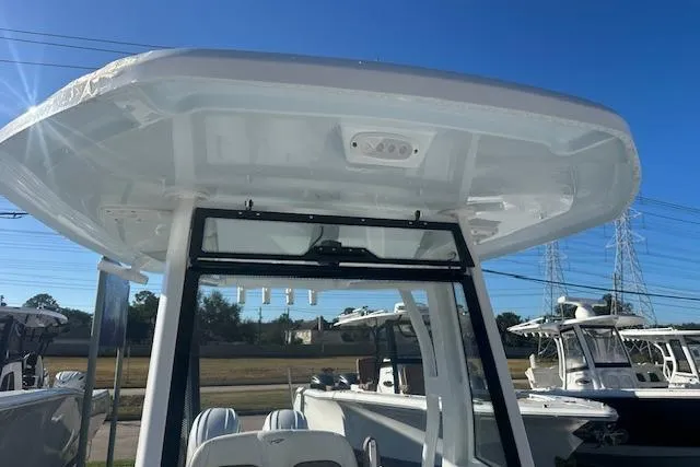 Slide: The Image of 2025 Tidewater 272 CC Adventure boat with T-top, parked outdoors under clear blue sky. - 12