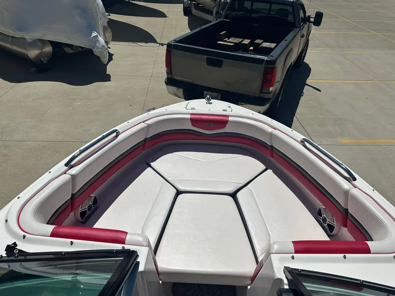 Slide: The Image of 2016 Chaparral Vortex 203 VRX boat interior with red and white seating, parked near a truck. - 5