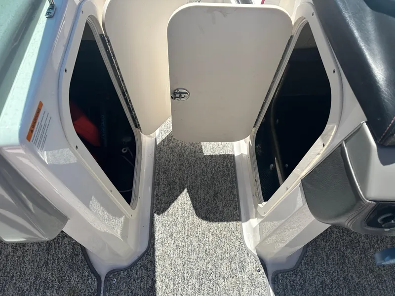 Slide: The Image of 2016 Chaparral Vortex 203 VRX boat storage compartments with open doors, carpeted floor. - 8