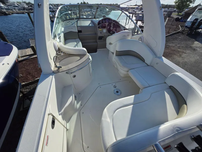 Slide: The Image of 2007 Sea Ray 260 Sundancer boat interior with white seating and helm, docked at marina. - 4