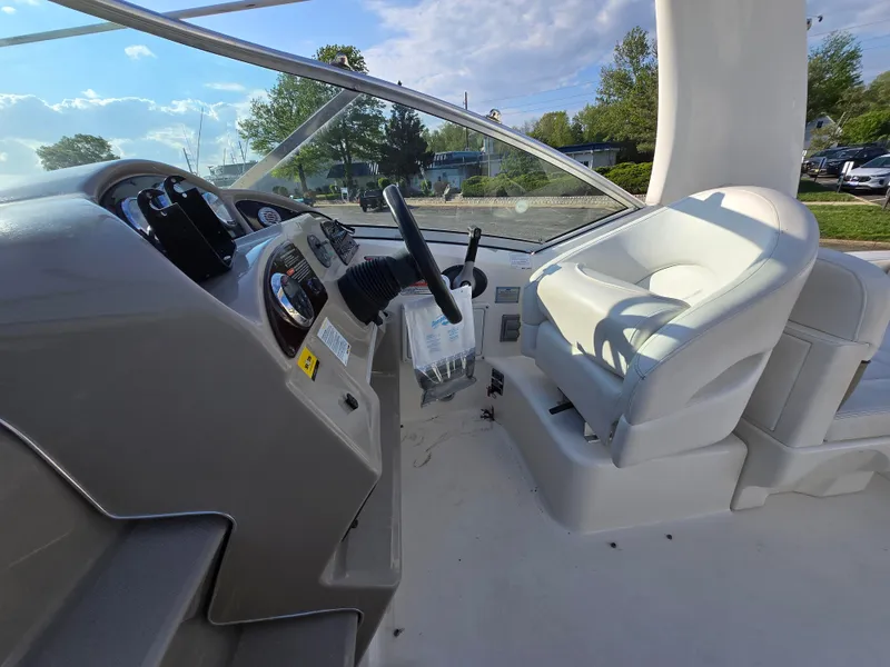 Slide: The Image of 2007 Sea Ray 260 Sundancer helm with steering wheel and captain's seat, under clear blue sky. - 8