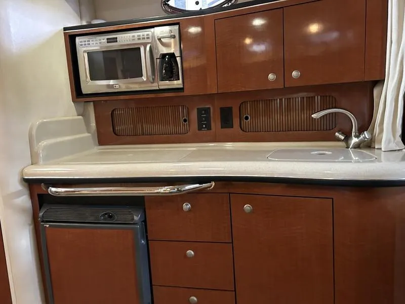 Slide: The Image of 2005 Sea Ray 320 Sun Dancer kitchen with microwave, sink, and wooden cabinetry. - 11