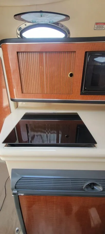 Slide: The Image of 2004 Sea Ray Sundancer 260 interior with stove and wooden cabinetry. - 11