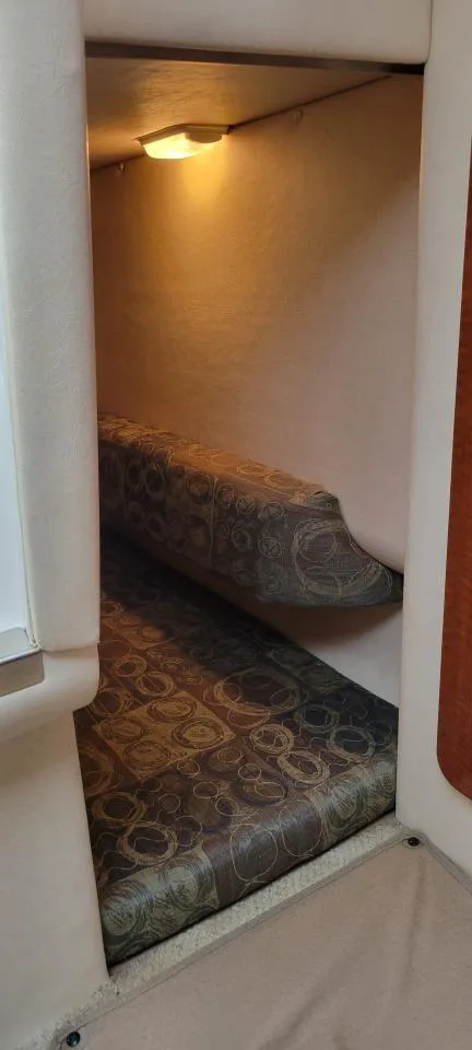 Slide: The Image of 2004 Sea Ray Sundancer 260 cabin interior with cozy lighting and patterned seating. - 13