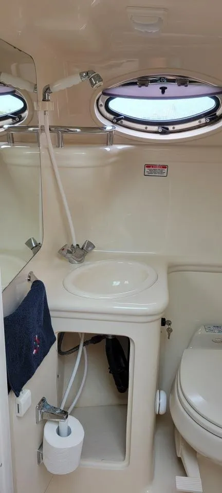 Slide: The Image of 2004 Sea Ray Sundancer 260 bathroom with sink, toilet, and porthole window. - 32