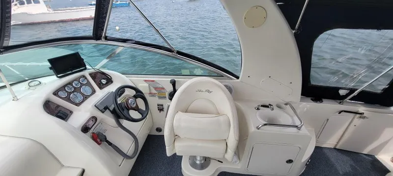 Slide: The Image of 2004 Sea Ray Sundancer 260 cockpit with steering wheel and control panel, overlooking water. - 35