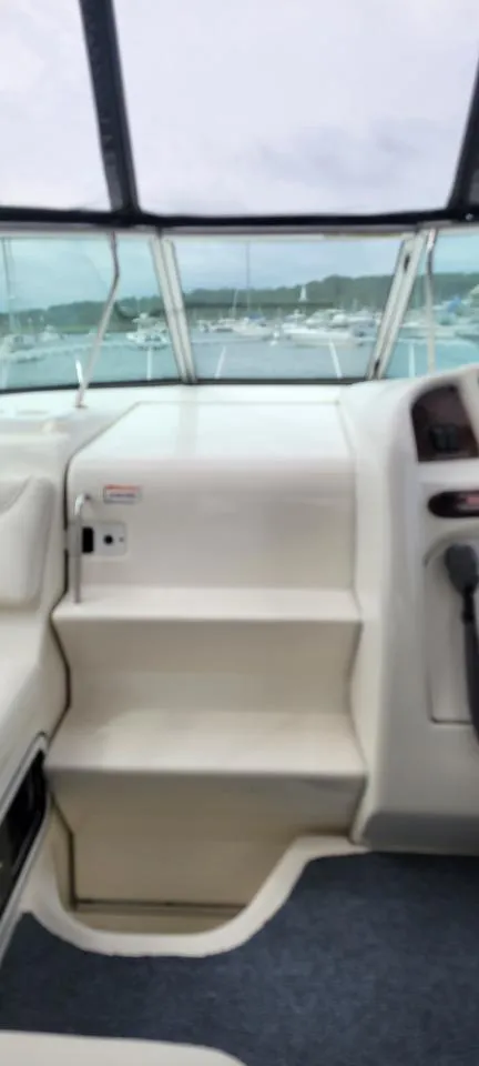 Slide: The Image of 2004 Sea Ray Sundancer 260 interior with helm and steps, overlooking marina. - 47