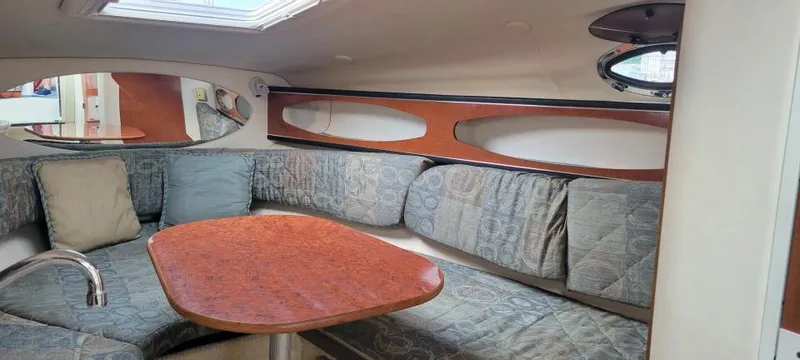 Slide: The Image of 2004 Sea Ray Sundancer 260 cabin interior with cushioned seating and wooden table. - 6
