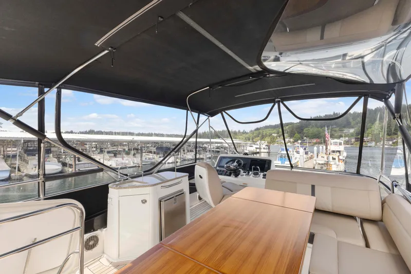 Slide: The Image of 2017 Sea Ray Fly 400 yacht interior with seating, table, and marina view. - 14