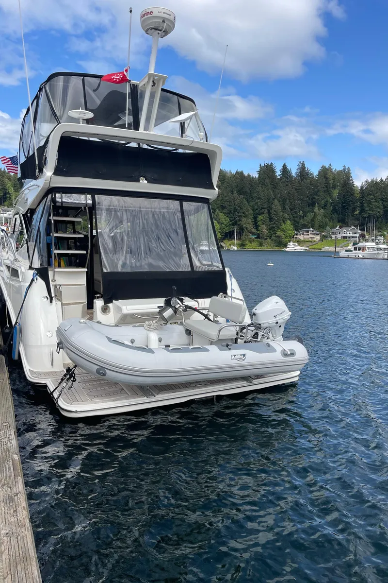 Slide: The Image of 2017 Sea Ray Fly 400 yacht docked on a serene lake with lush forest backdrop. - 61