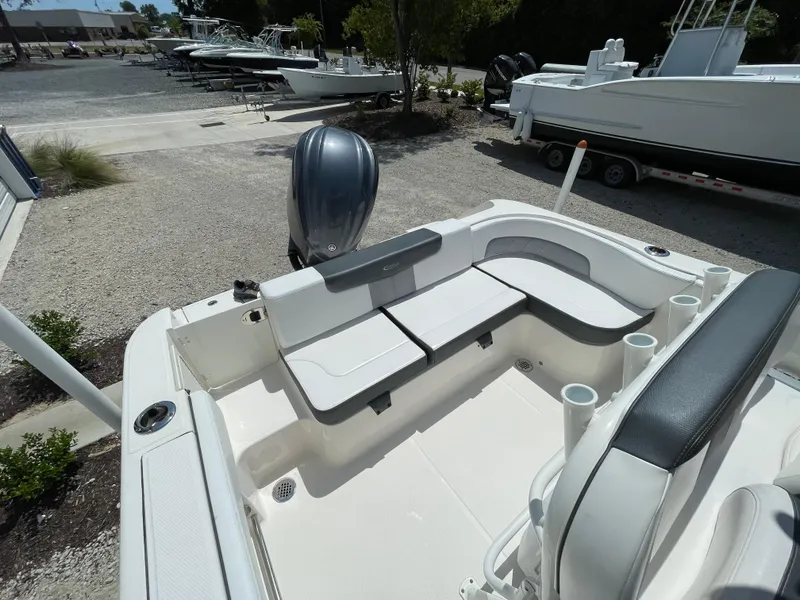 Slide: The Image of 2021 Robalo R242 Explorer boat interior with seating and motor, parked on gravel. - 12
