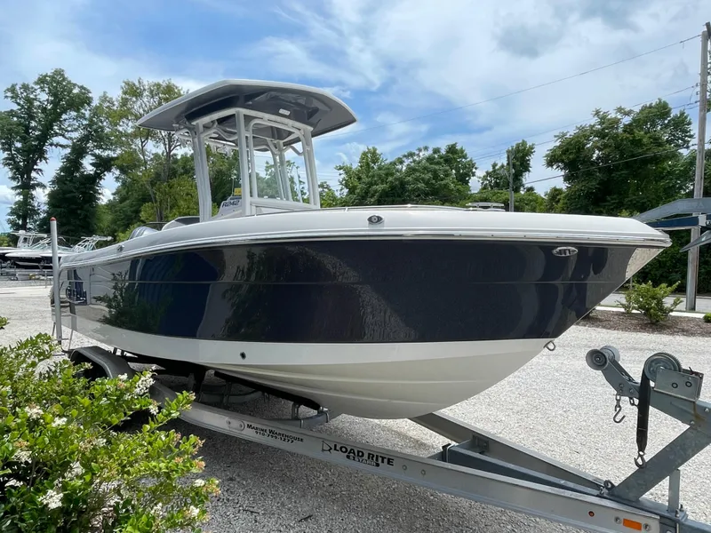Slide: The Image of 2021 Robalo R242 Explorer boat on trailer, parked outdoors with trees in background. - 5