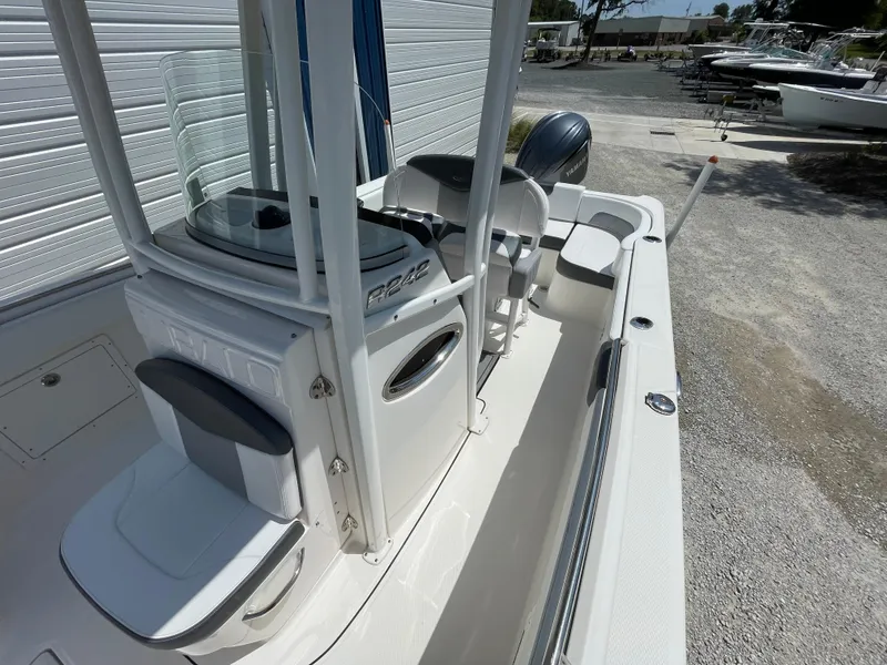 Slide: The Image of 2021 Robalo R242 Explorer boat interior with seating and console, parked outdoors. - 8
