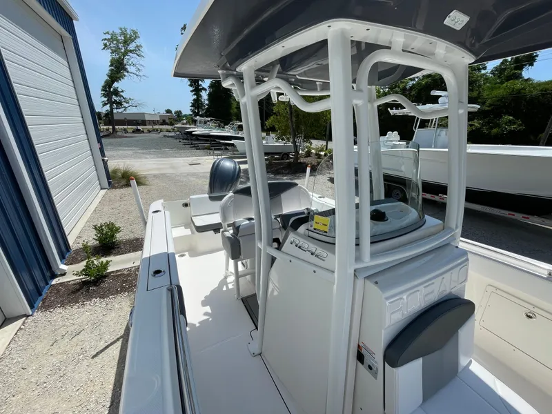 Slide: The Image of 2021 Robalo R242 Explorer boat, white interior, docked near a storage facility. - 9