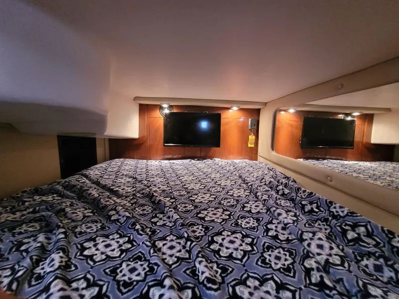 Slide: The Image of Cozy cabin interior of 2006 Regal 3060 Window Express with patterned bedding and wall-mounted TV. - 16